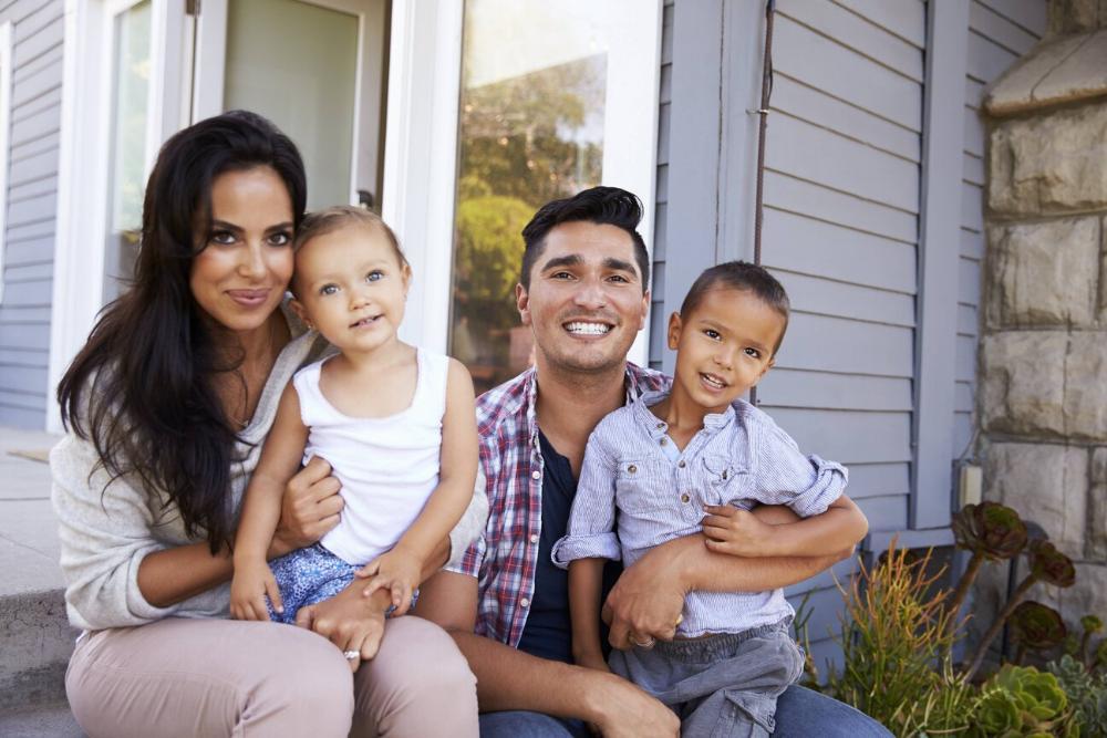 father, mother, and two children smiling while sitting on porch in Urbandale
