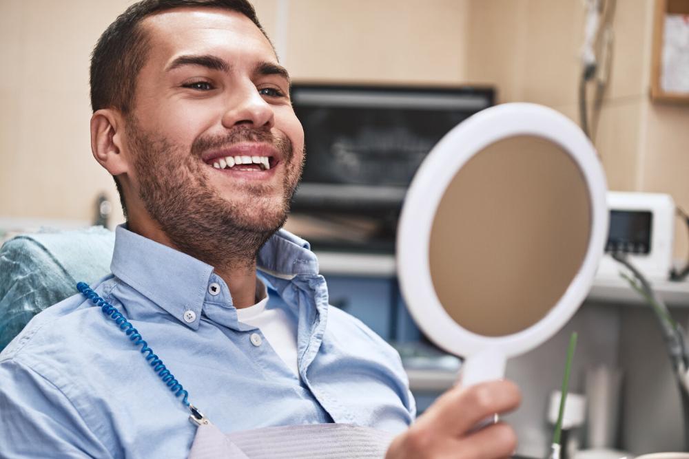 man smiling in mirror after getting periodontal treatment in urbandale