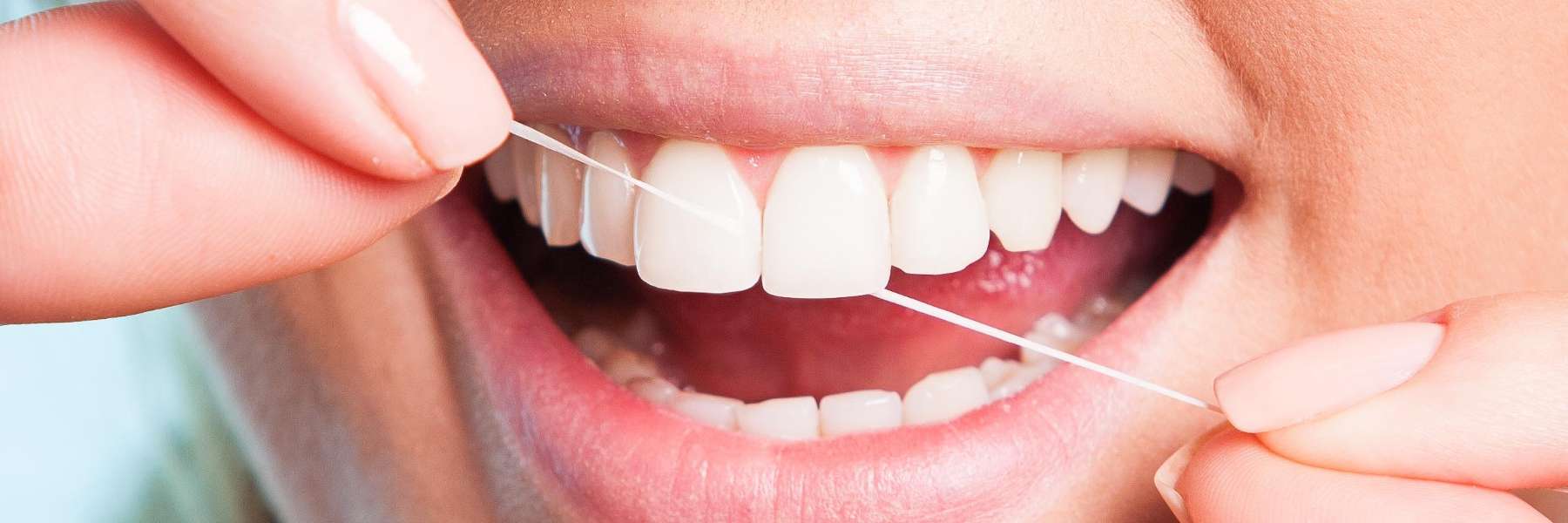 close up of woman using dental floss between front teeth
