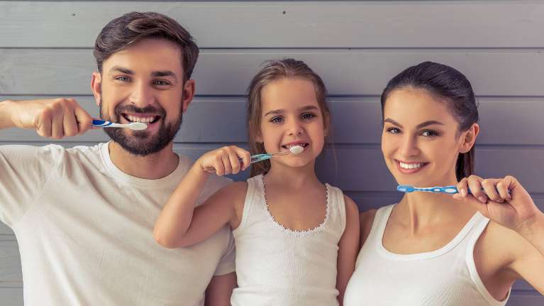 Dad, mom, and daughter brushing teeth in urbandale